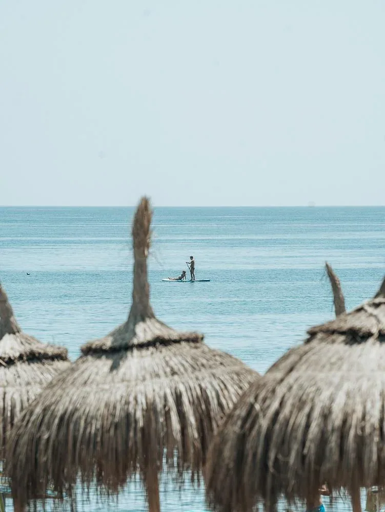 Un paddle surf en el agua, visto entre las sombrillas