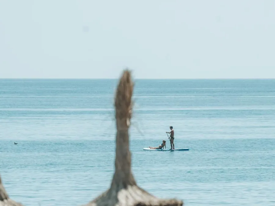 El mar desde la orilla, con un paddle surf al fondo