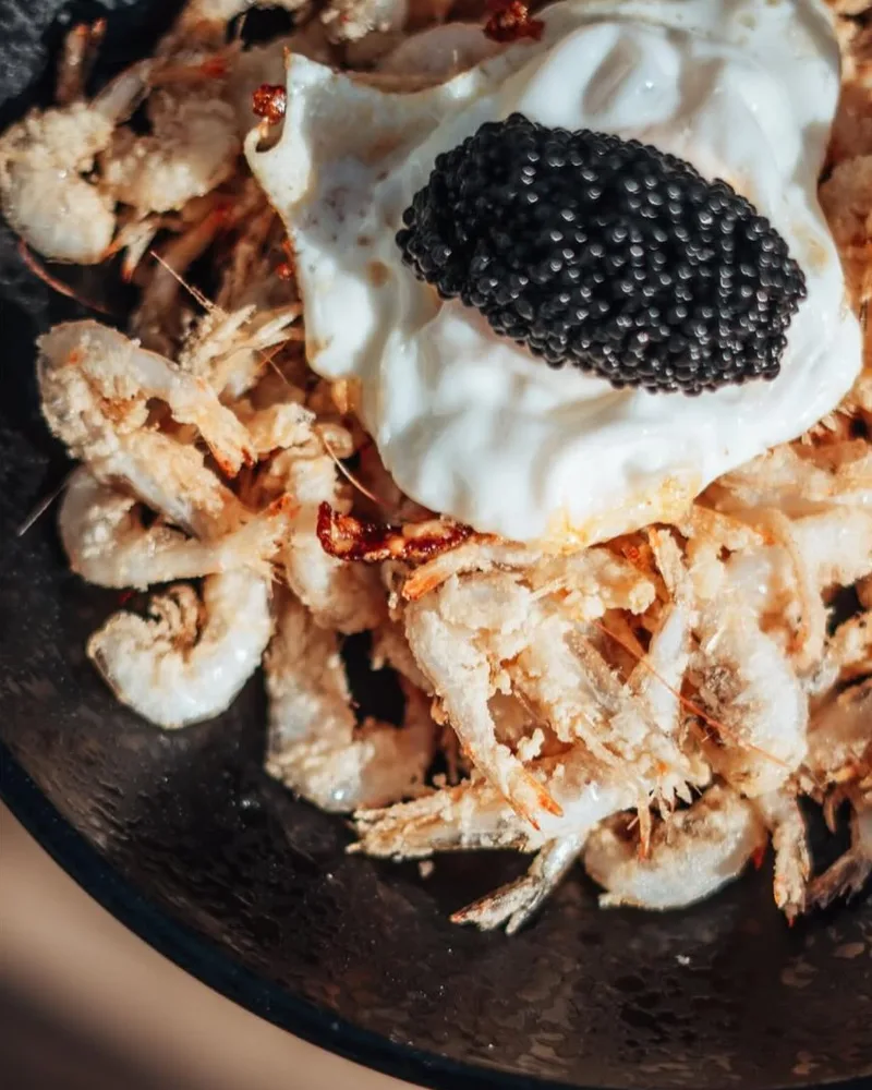 Huevo frito con caviar sobre quisquillas fritas